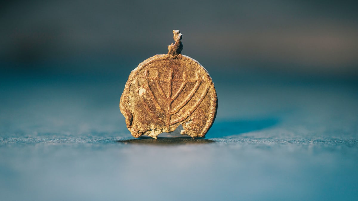 Ancient lead pendant showing carved menorah symbol from seventh century Jerusalem excavation
