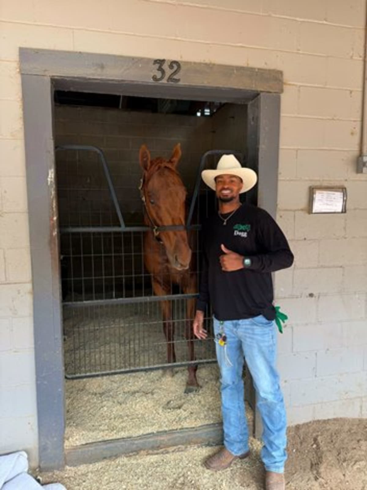 Olympic gold medalist Quincy Hall standing trackside watching Thoroughbred racehorses train at South Carolina facility