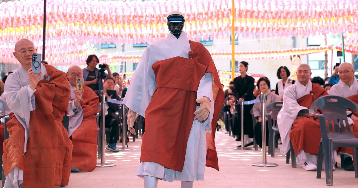 Humanoid robot Gabi in gray Buddhist robes bowing during ordination ceremony at Seoul temple