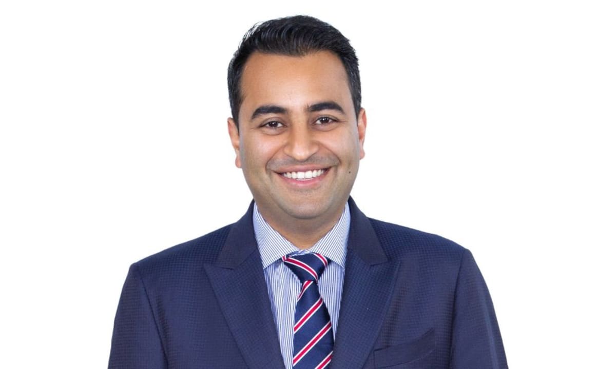 Mortgage adviser Satyan Mehra reviewing documents at desk, helping clients secure property loans