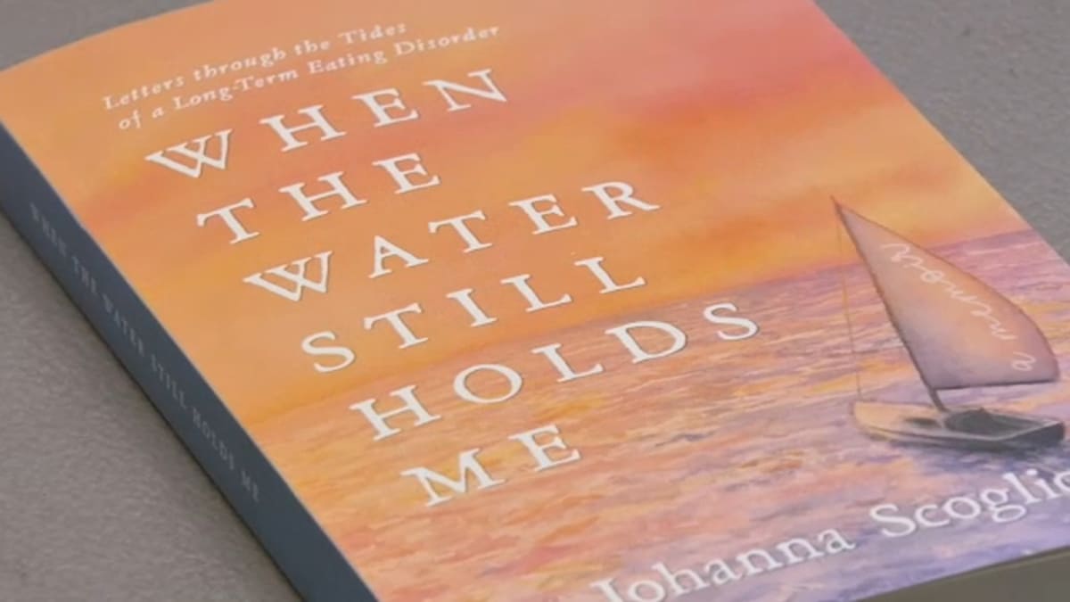 ** Author Johanna Scoglio holding her memoir about decades-long eating disorder recovery journey