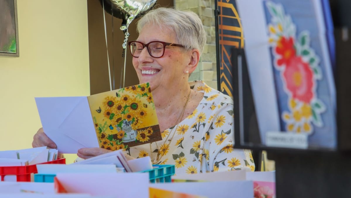 Cancer survivor Linda Smolinski holding colorful handmade greeting cards at cancer treatment center