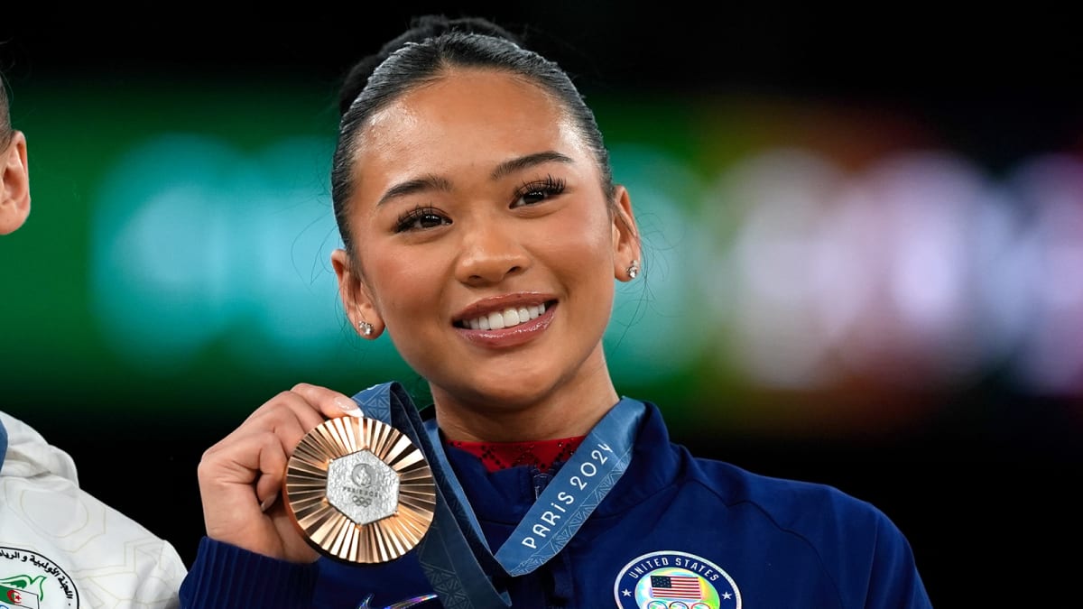 Olympic gymnast Suni Lee performing on uneven bars in competition wearing team USA leotard