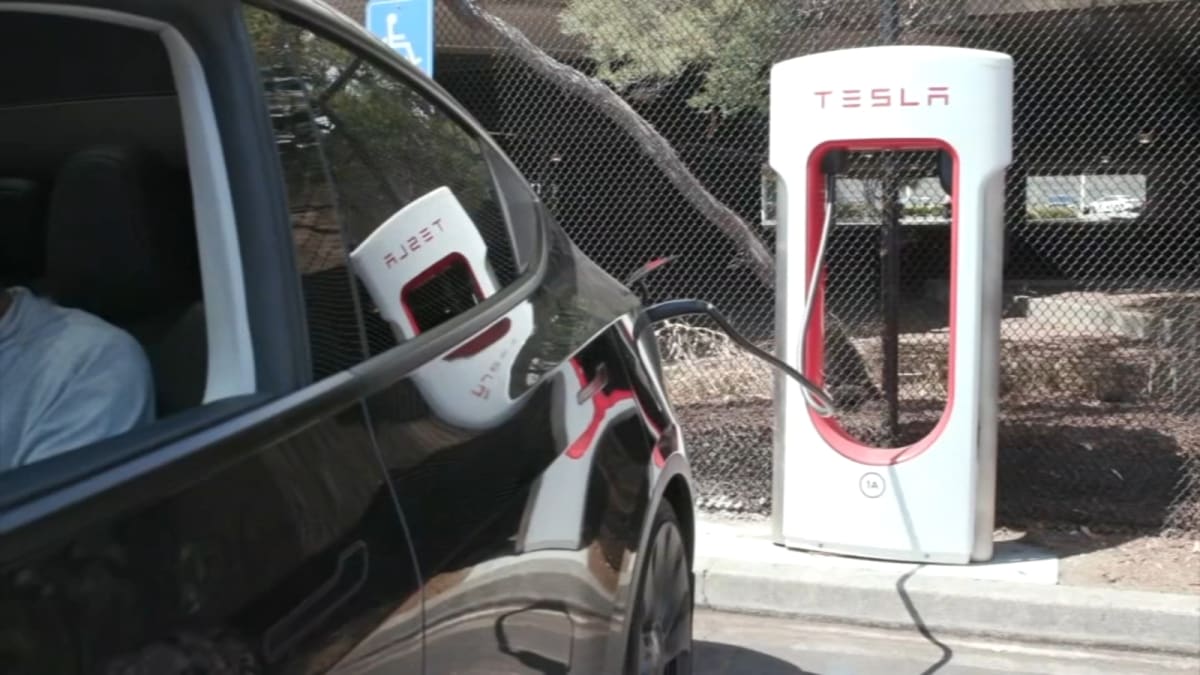 Electric vehicle plugged into charging station in California with blue sky background