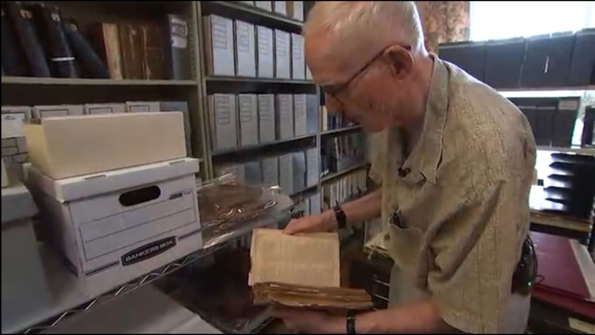 Elderly man examining historical maps and documents in archive room at Germantown Historical Society