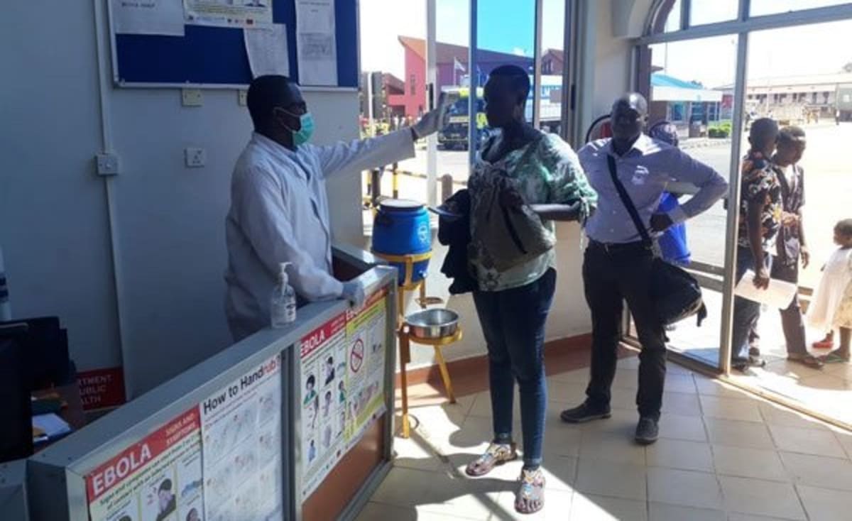 ** Healthcare workers in protective equipment conducting health screenings at East African border crossing