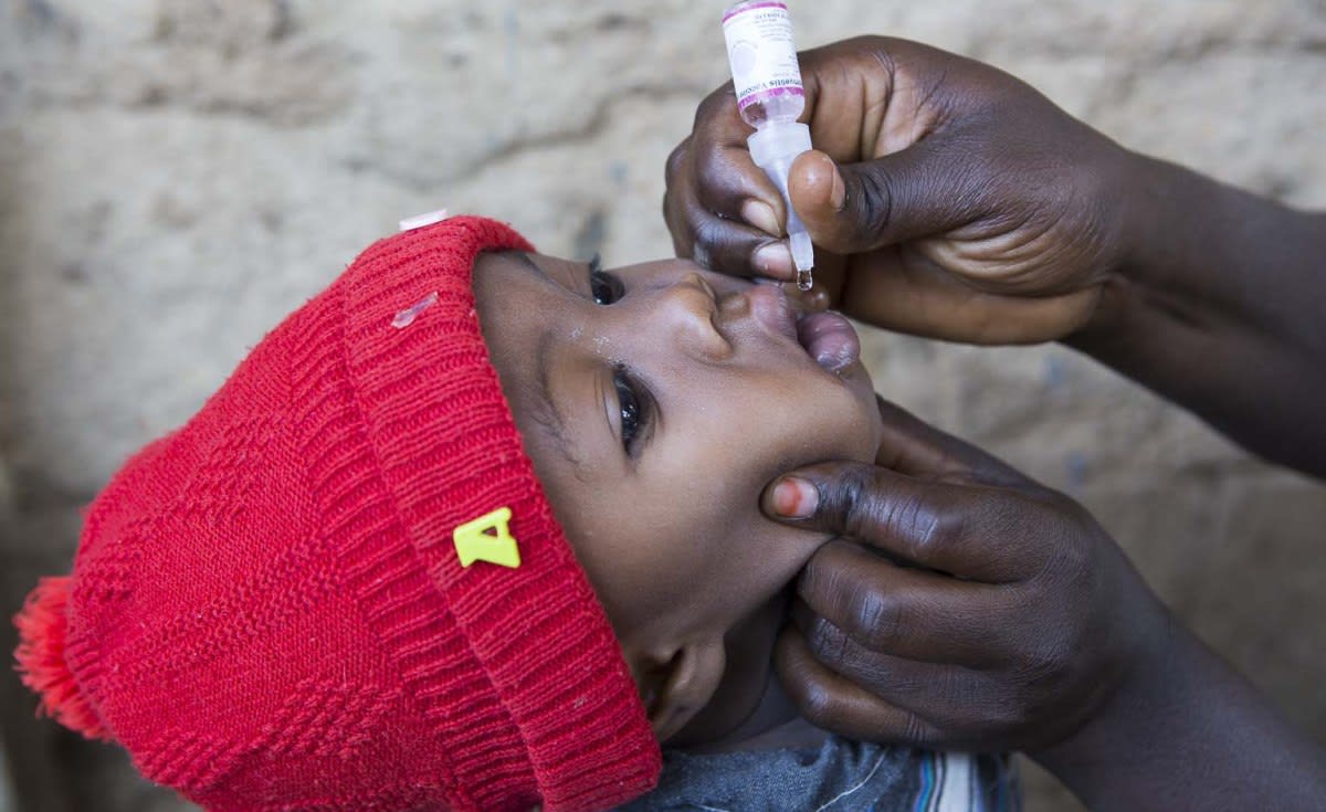 Healthcare worker administering polio vaccine to young child in Botswana clinic setting