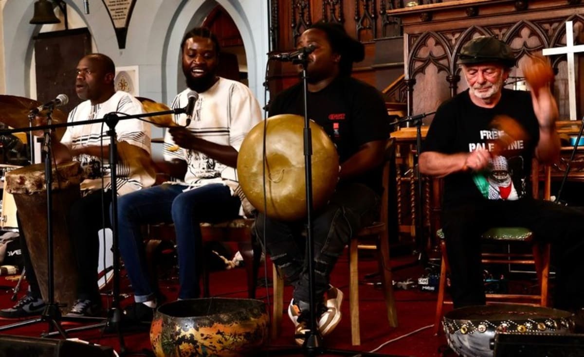 Diverse group of musicians and activists gathering inside Cape Town church for refugee solidarity concert