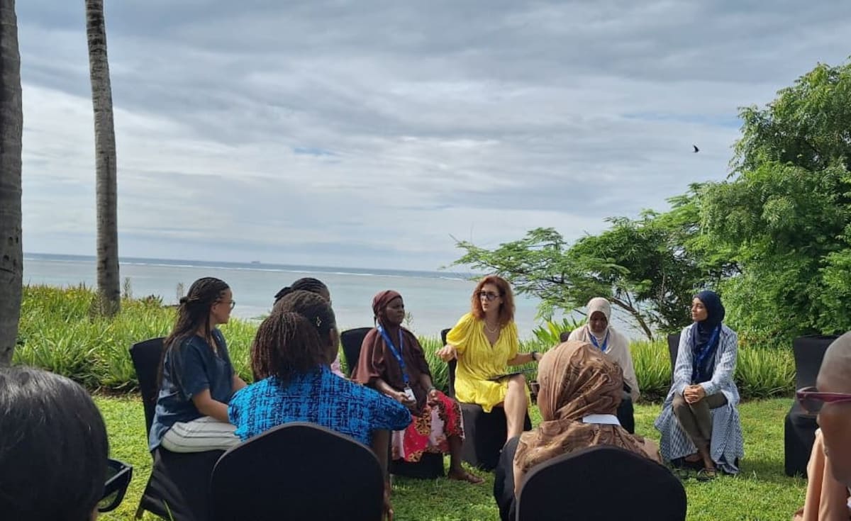 Three Kenyan women leaders sit together overlooking the Indian Ocean at conservation conference
