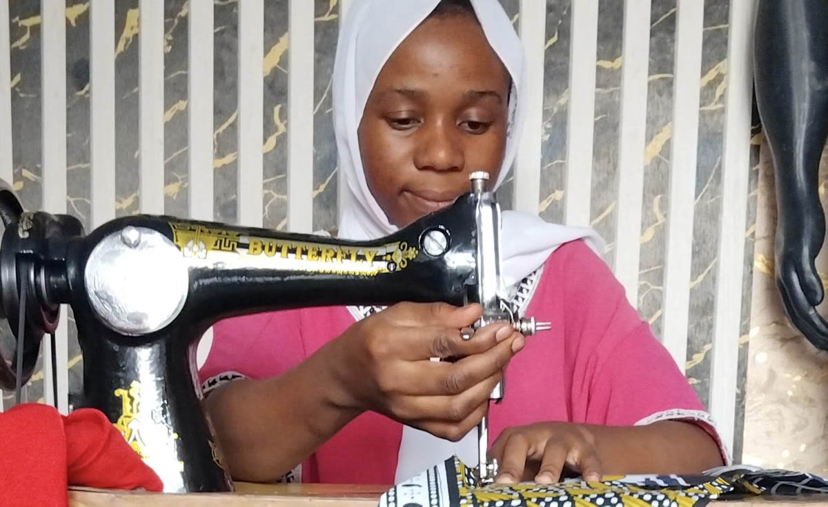 Workers in a Tanzanian garment factory cutting and sewing colorful fabrics into clothing