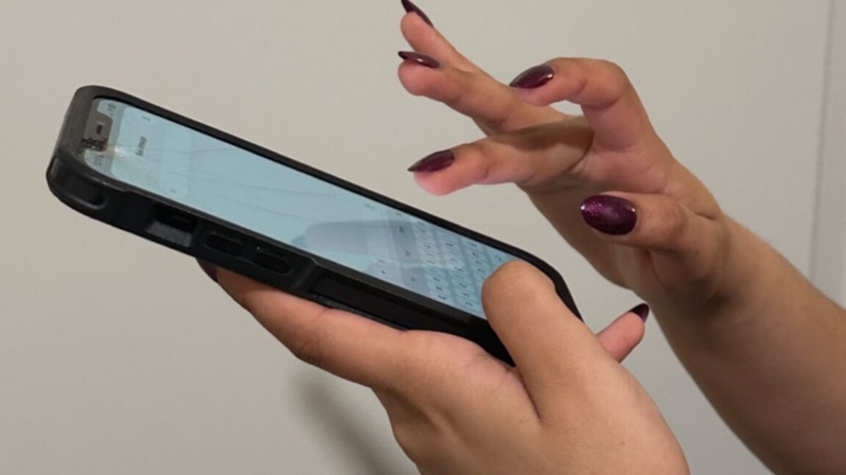 Clear nail polish being tested on smartphone touchscreen with tweezers holding polish sample