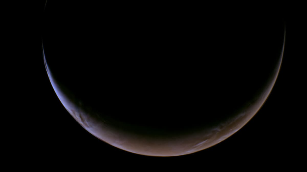 Crescent Mars with wispy atmosphere glowing against black space captured by NASA Psyche spacecraft
