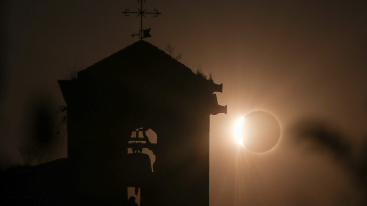 Total solar eclipse showing white corona over historic Spanish church in Duratón