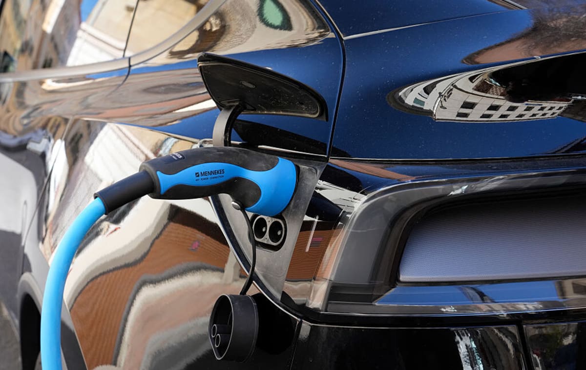 ** Electric vehicle connected to charging station with battery health indicator display showing strong performance