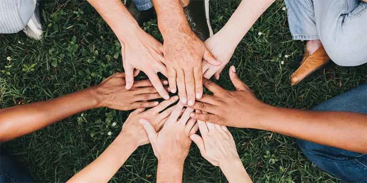 Diverse group of people from different nations standing together holding interconnected hands in unity