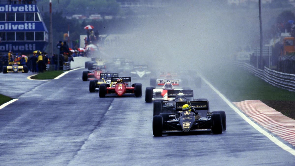Ayrton Senna driving black and gold Lotus race car in heavy rain at 1985 Portuguese Grand Prix