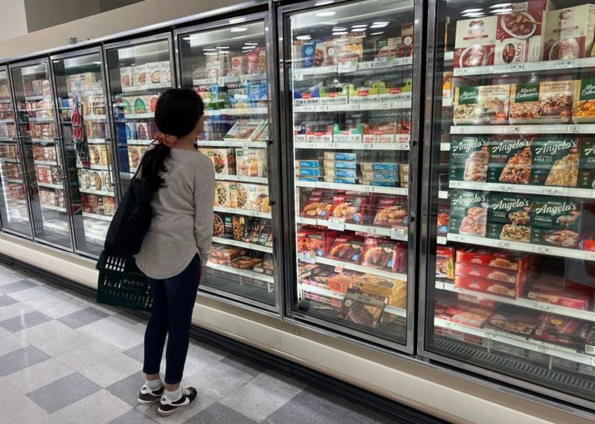 Colorful frozen vegetables in clear plastic bags inside grocery store freezer section