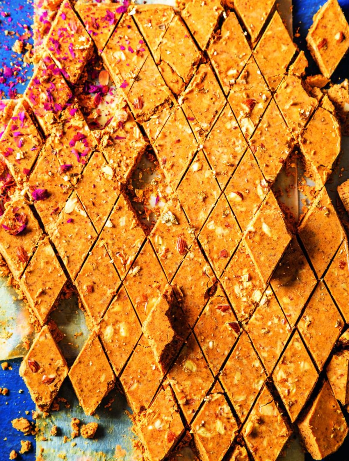 Golden squares of chana magaj Indian fudge topped with sliced almonds on baking paper