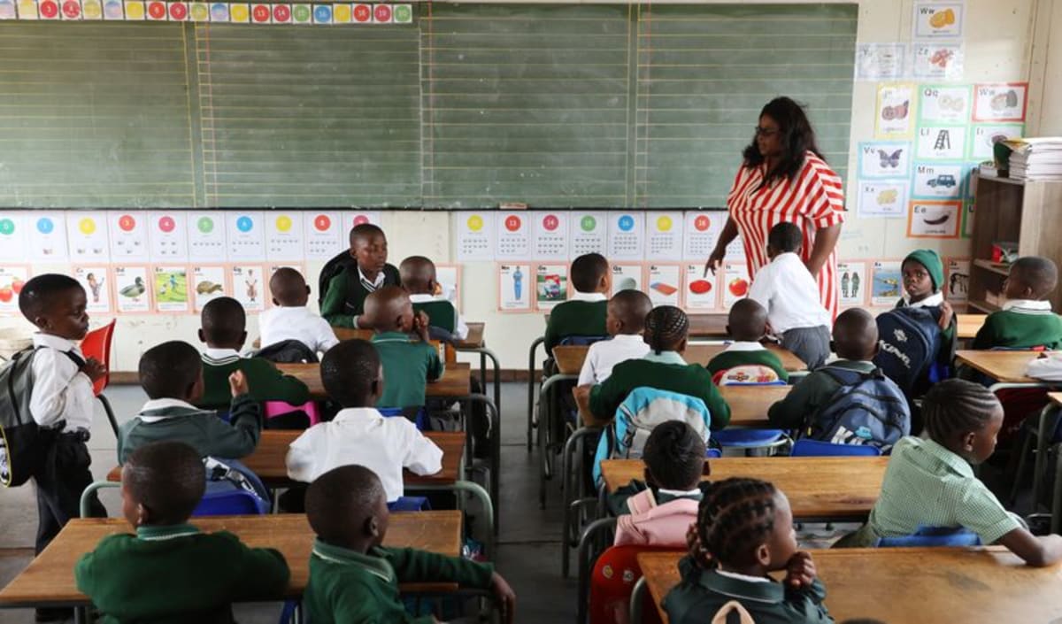 South African primary school teacher welcoming young students on first day of school