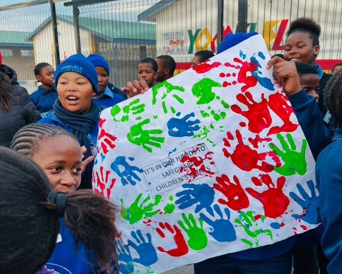 Soul Buddyz Club members holding a handmade poster during a South African community activity