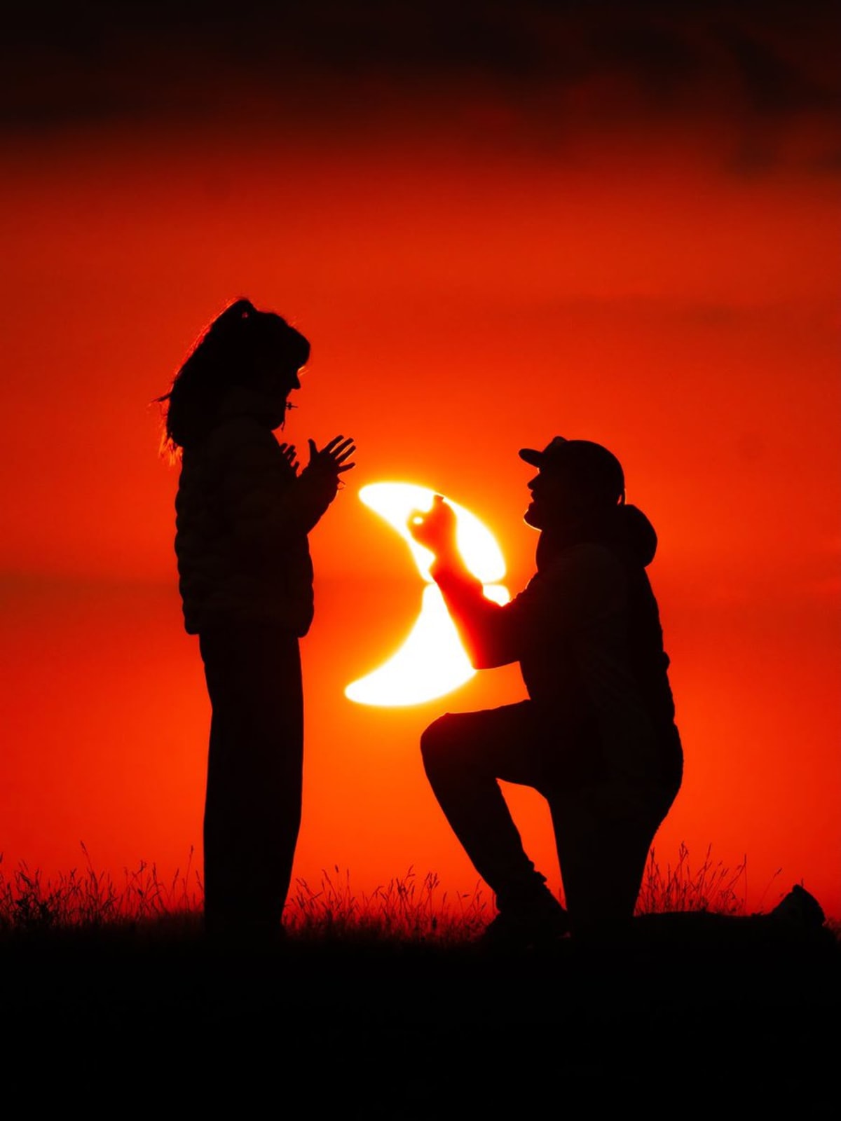 Couple silhouetted against French Alps mountains during solar eclipse proposal moment