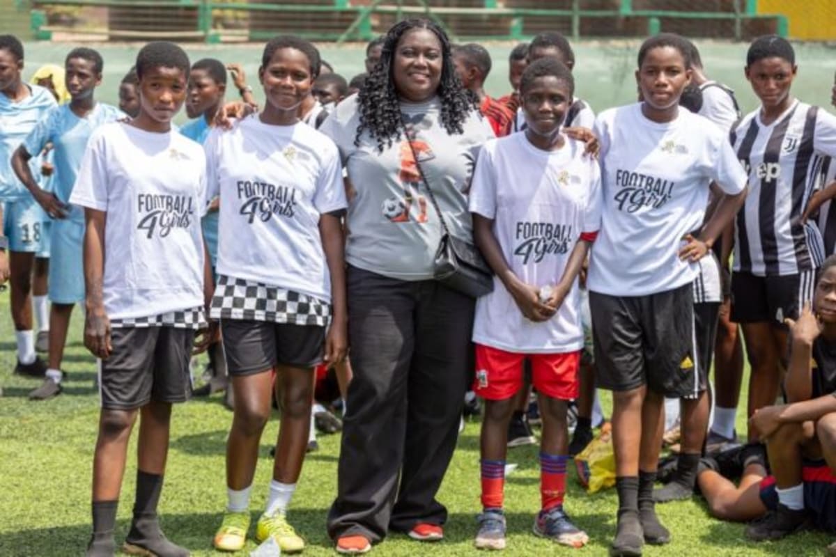 Young girls in sports uniforms playing football at outdoor complex in Ghana