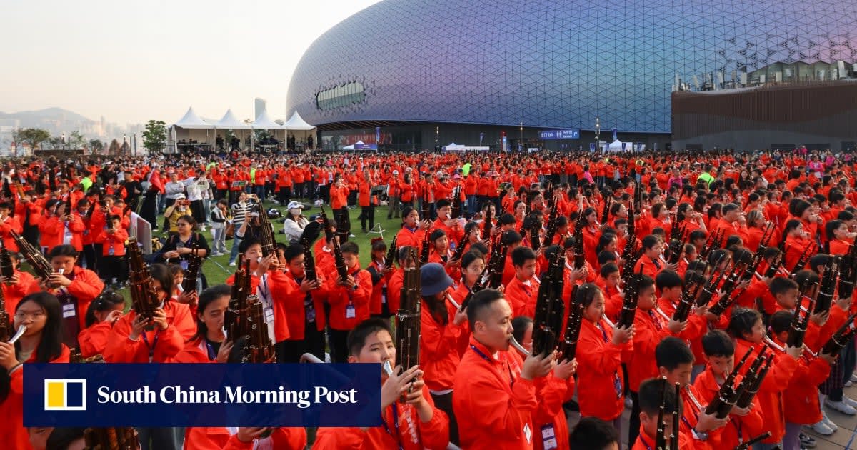 Large ensemble of musicians with traditional instruments performing together at Hong Kong sports venue