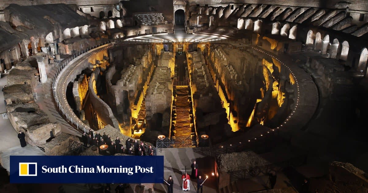Pope Leo carrying wooden cross during Good Friday procession at Rome's Colosseum with torch bearers
