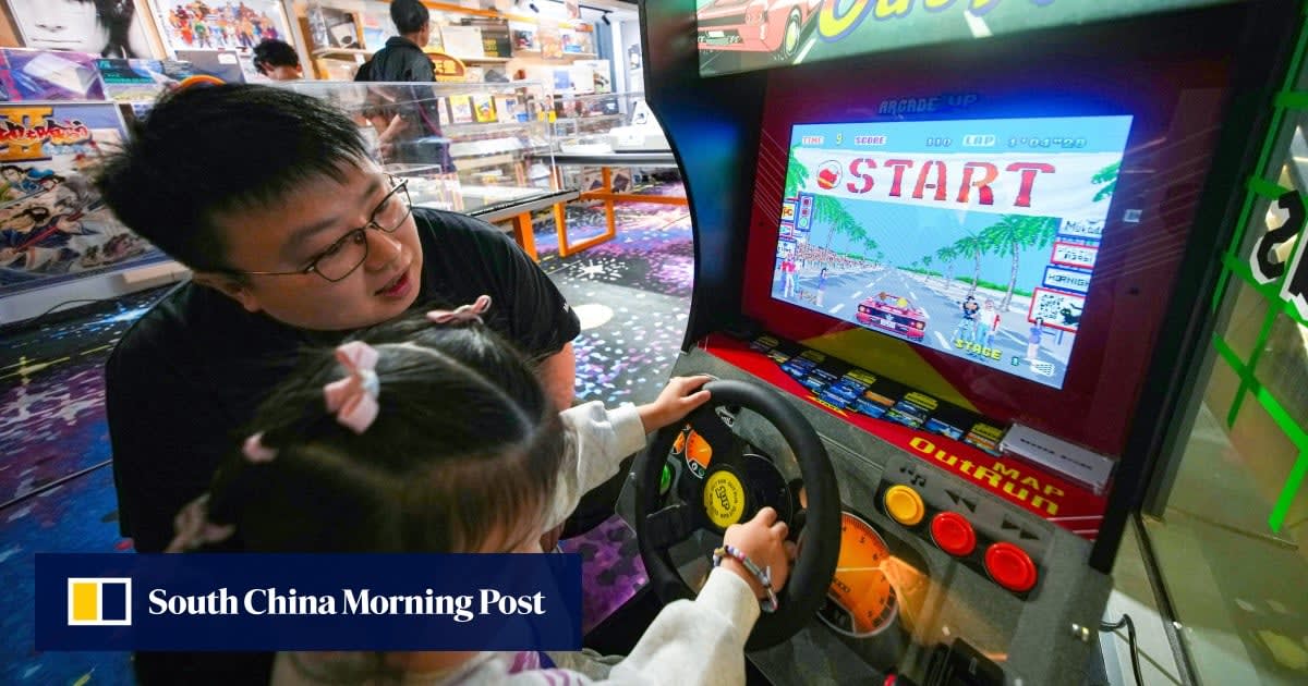 Parent and child sitting together playing video games on a couch, smiling and engaged