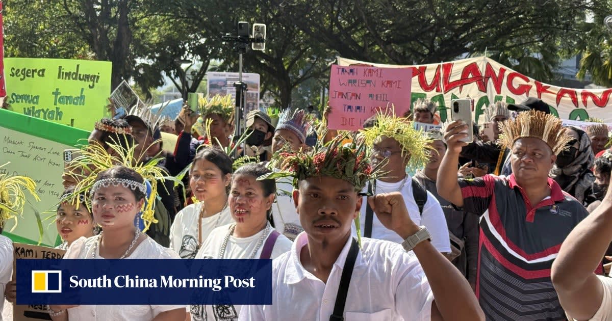 Orang Asli protesters in traditional headgear marching peacefully through Putrajaya holding signs demanding land rights recognition