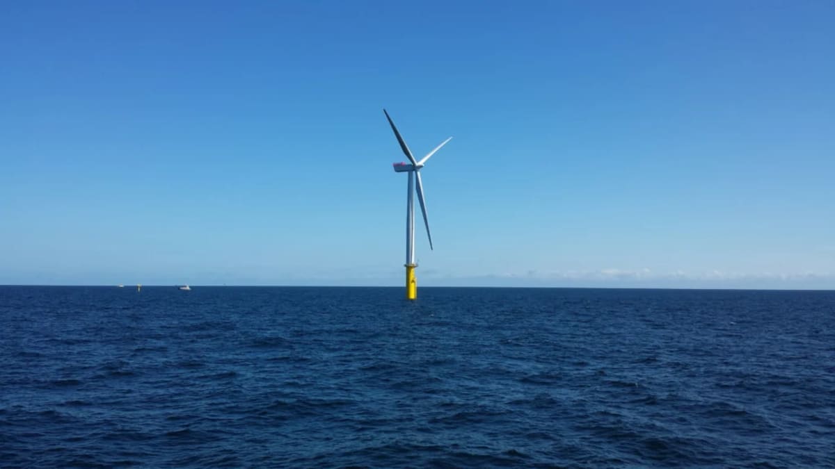 ** Offshore wind turbines standing in deep ocean water generating renewable energy at sunset