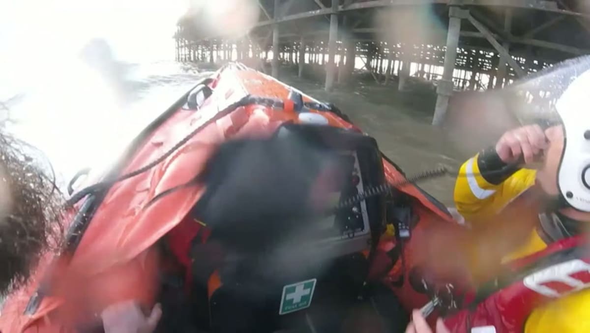 RNLI lifeboat crew volunteers performing rescue operation near Blackpool Pier in rough water conditions