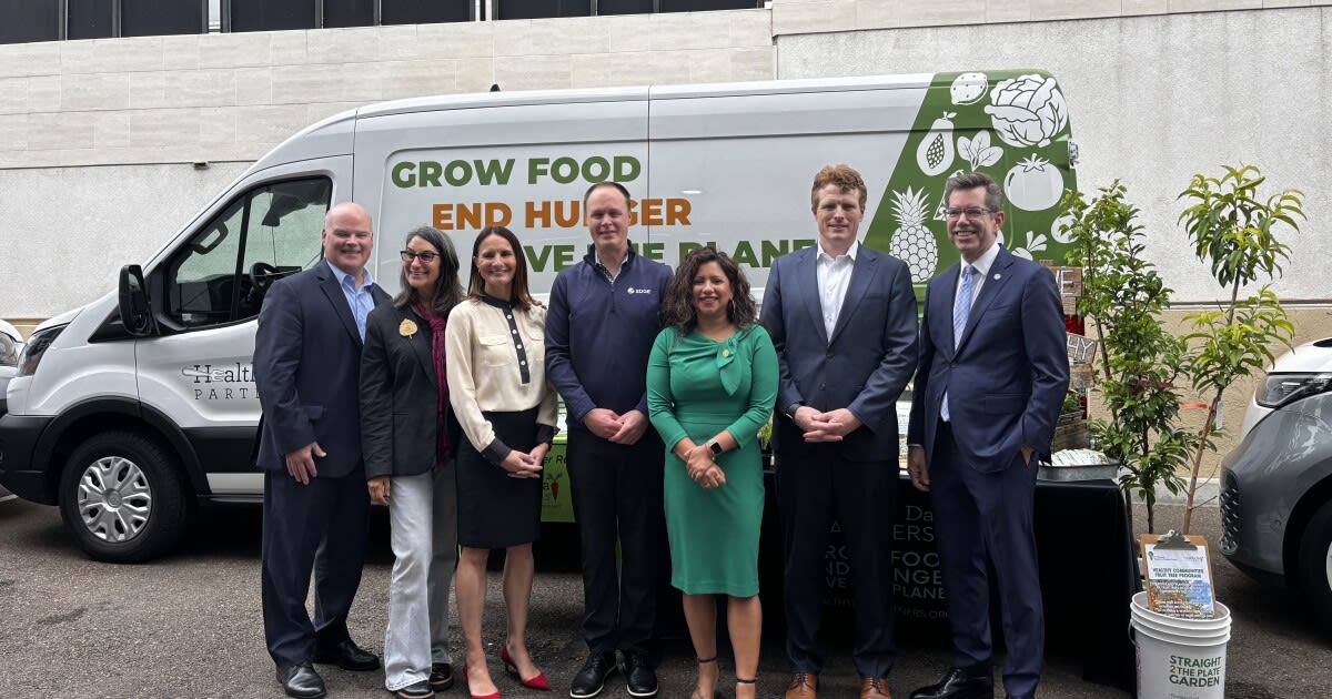 Electric vehicle with nonprofit logo parked outside senior center in San Diego