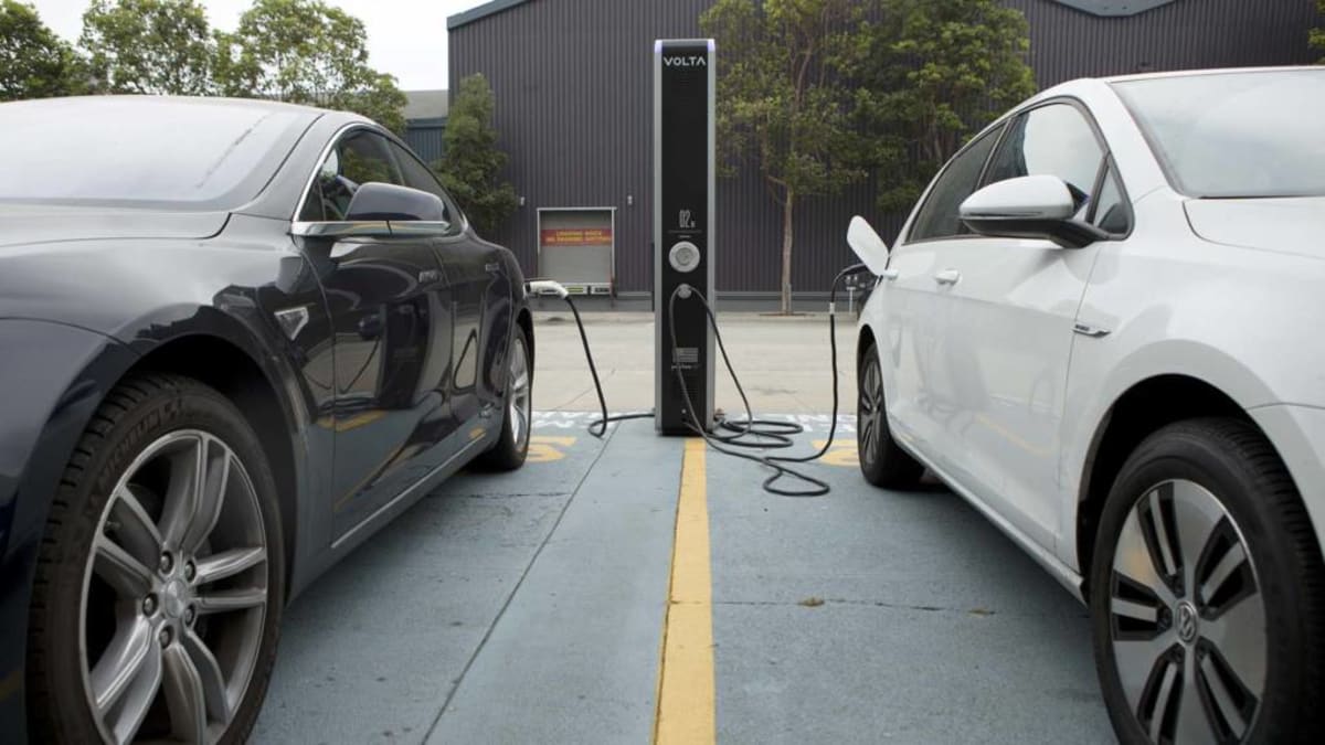 Electric vehicle plugged into charging station with modern home in background