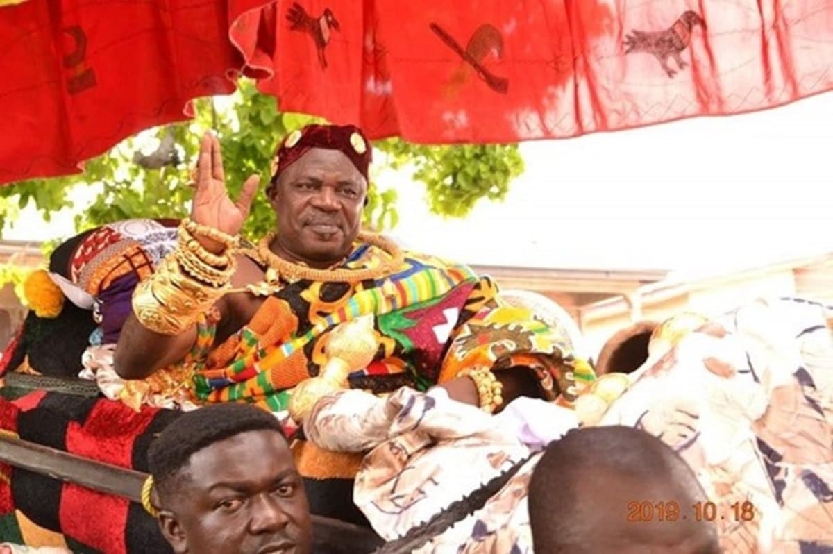 Traditional Ghanaian chief in ceremonial attire addressing community members during interfaith celebration