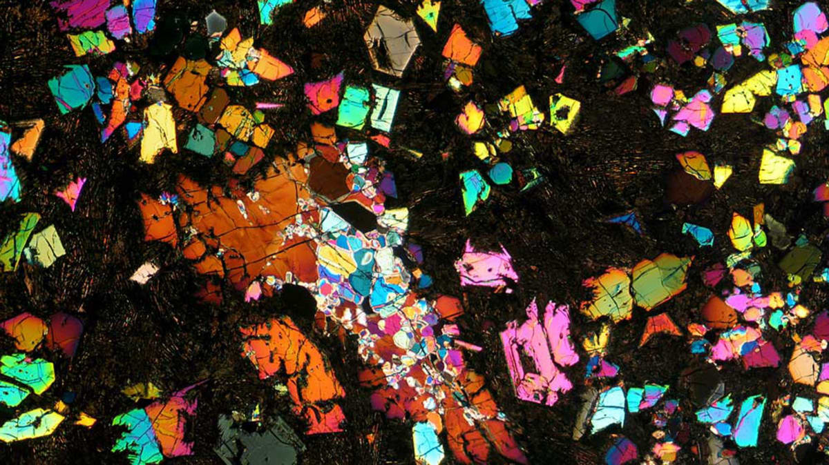 Rainbow kaleidoscopic angrite meteorite NWA 12774 viewed under cross-polarized light showing mineral structures