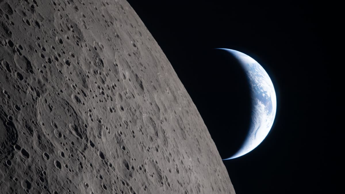 Crescent Earth setting behind the moon's surface as seen from Artemis II spacecraft