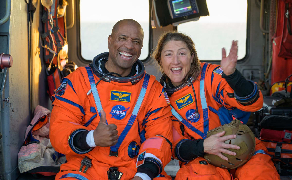Astronauts Victor Glover and Christina Koch smiling and waving on recovery ship after Artemis 2 splashdown