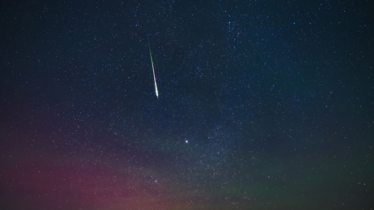 ** Wide-angle camera on tripod pointed at starry night sky capturing meteor shower