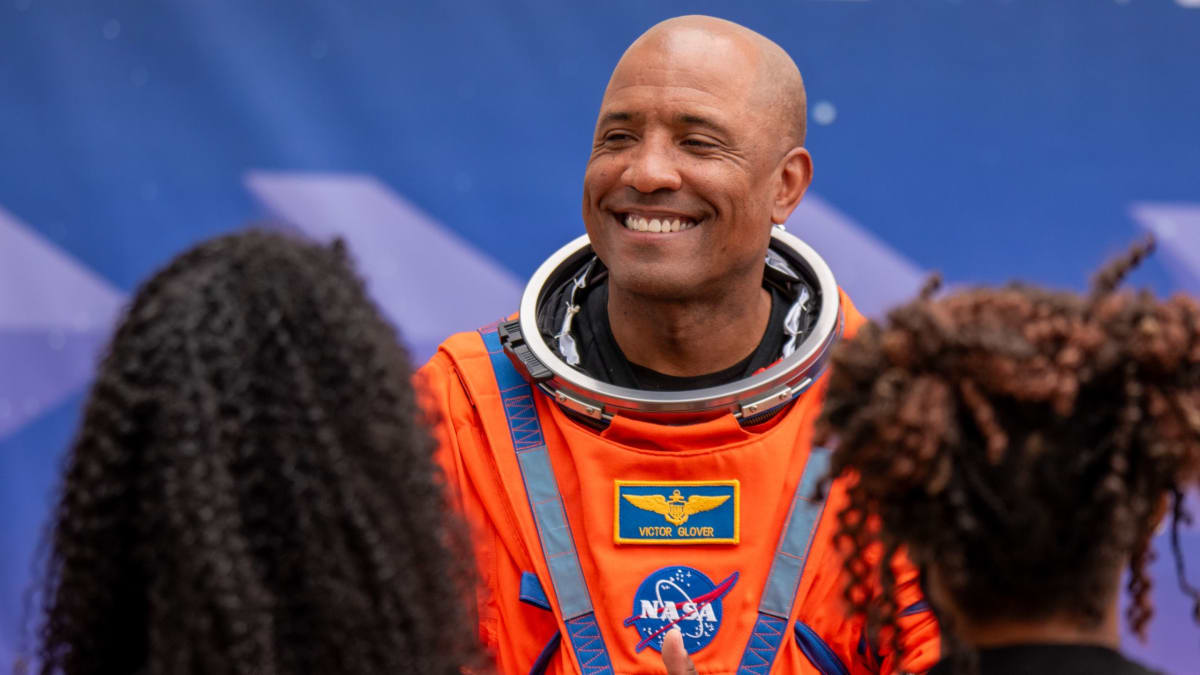 Astronaut Victor Glover in flight suit smiling with family members before Artemis mission