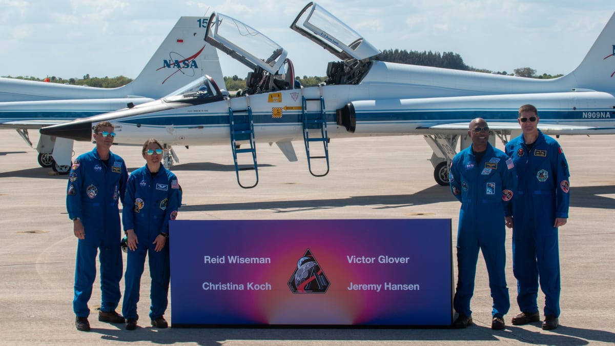 Four Artemis 2 astronauts standing on tarmac beside T-38 jets at Kennedy Space Center