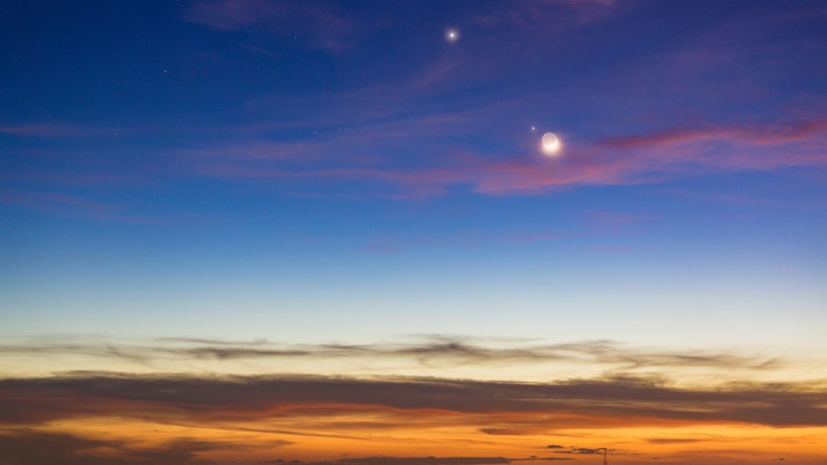 Moon shining near bright Jupiter and Venus in twilight sky after sunset