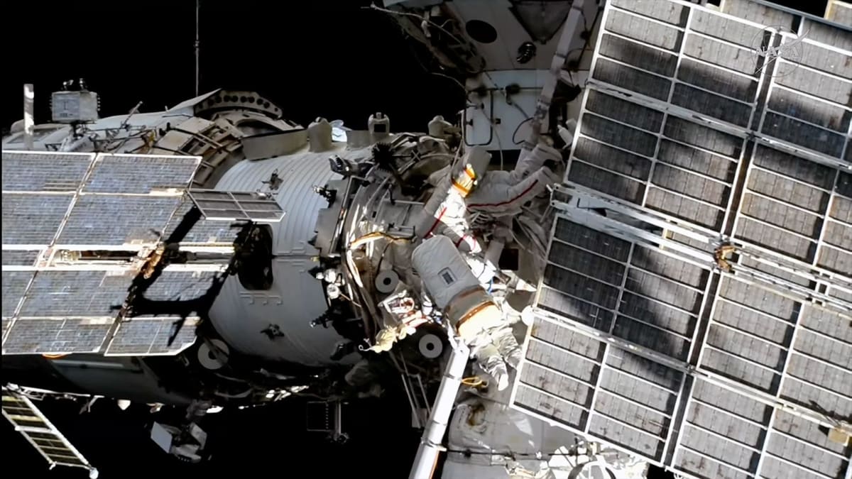 Two cosmonauts in spacesuits working outside the International Space Station installing scientific equipment