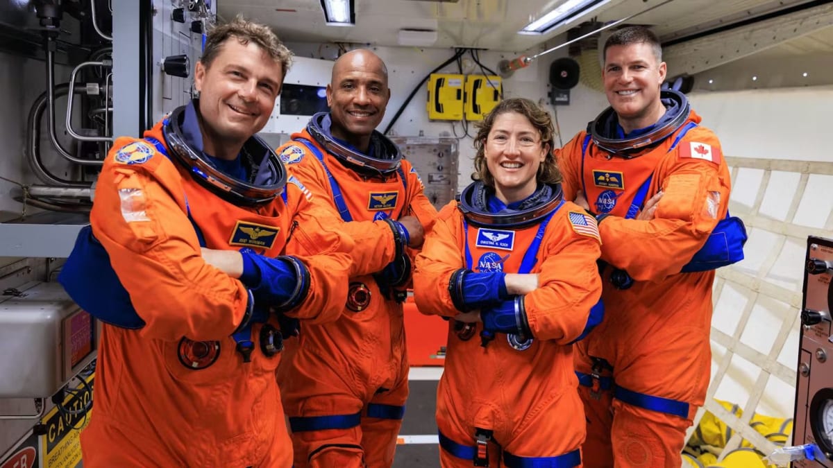 NASA astronaut Victor Glover in orange flight suit smiling at camera before Artemis mission