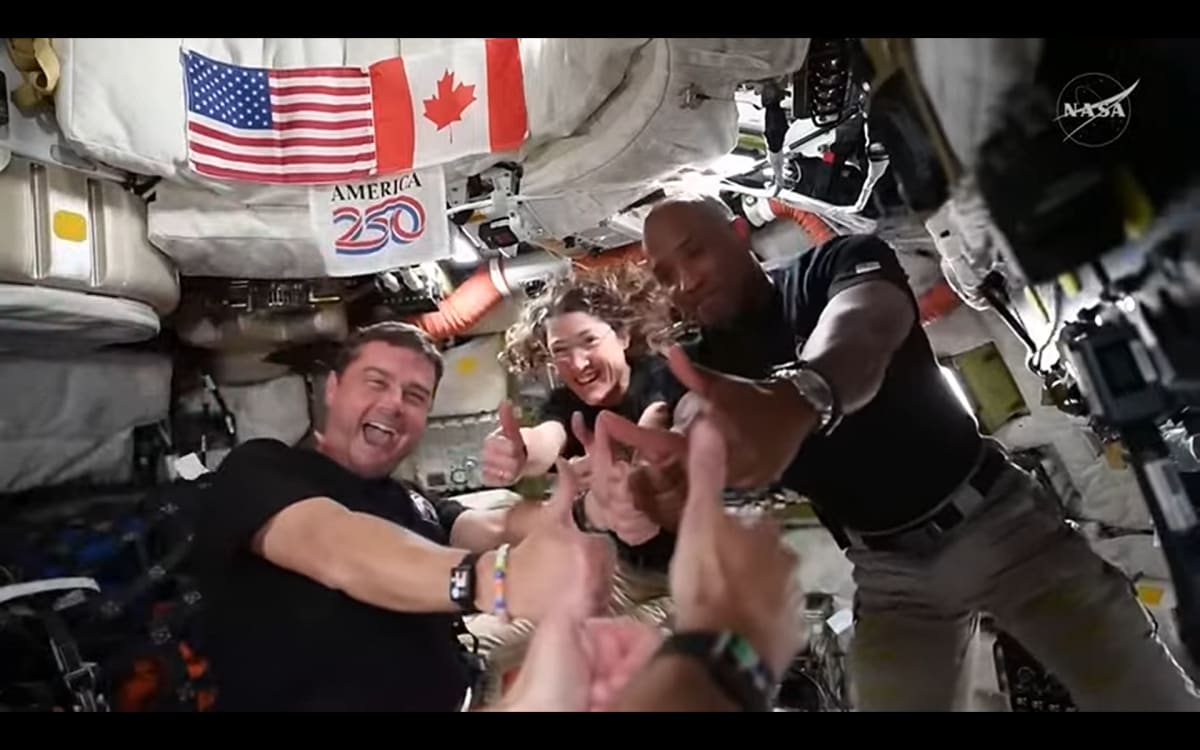 Four Artemis 2 astronauts in blue flight suits speaking with President from spacecraft near moon