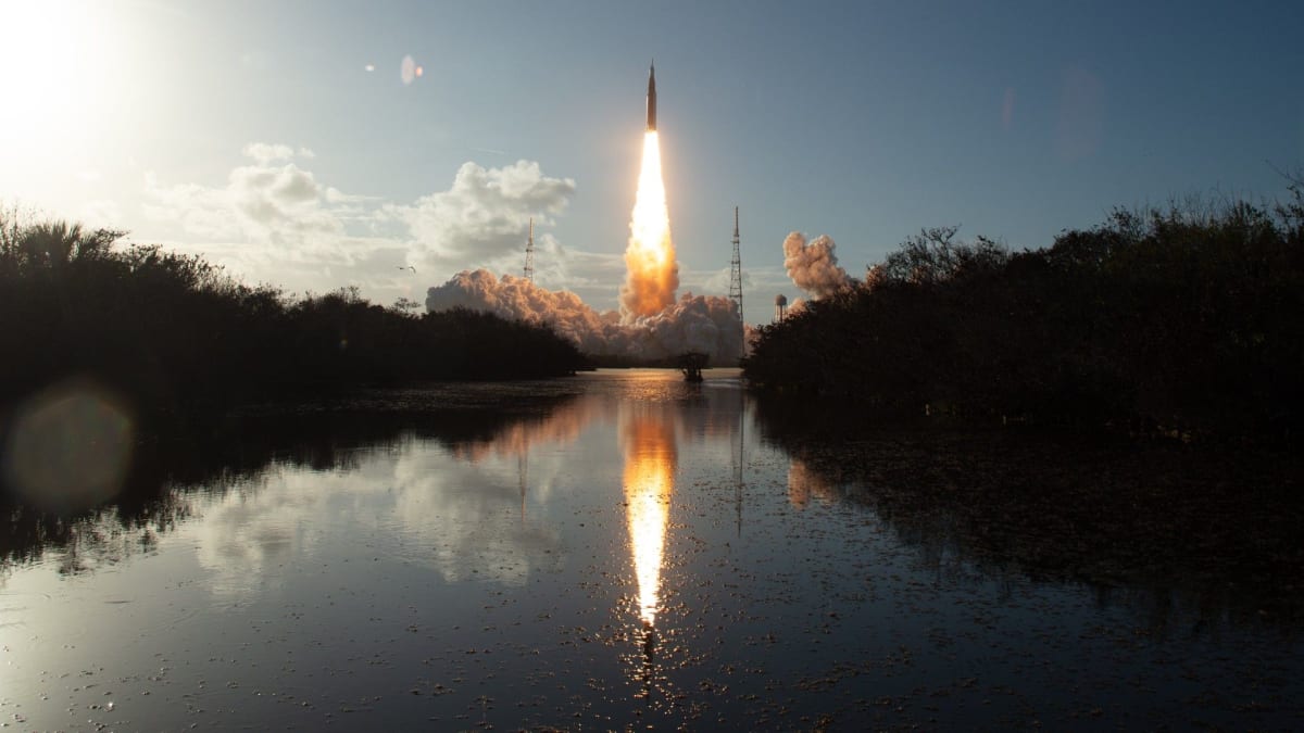 NASA Space Launch System rocket launches Artemis 2 mission with bright flames reflected in water