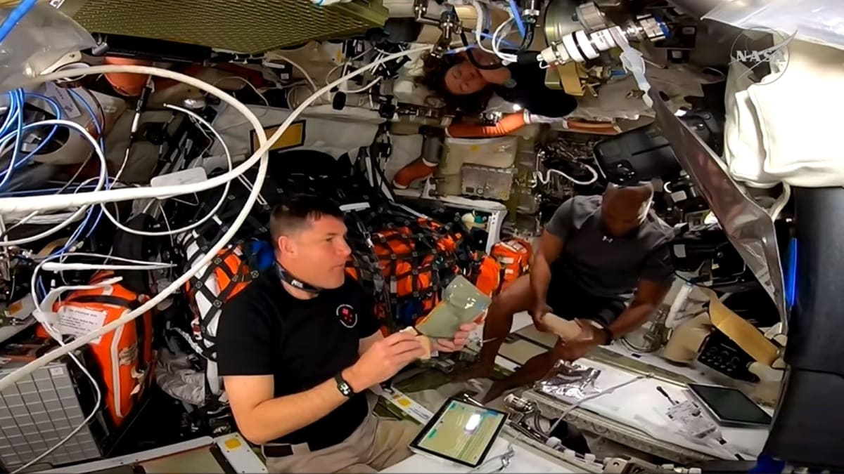 NASA astronaut Victor Glover taking towel bath inside Orion spacecraft with crewmates nearby