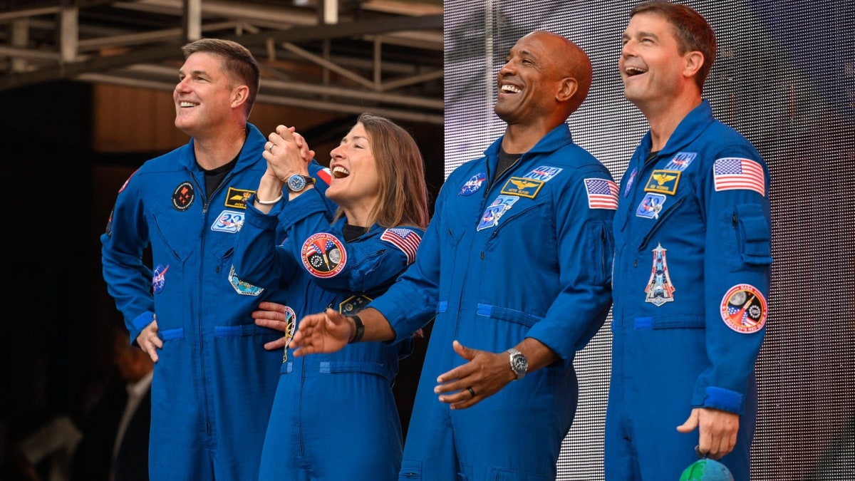 ** Four Artemis II astronauts standing on stage at Red Rocks Amphitheatre addressing large crowd