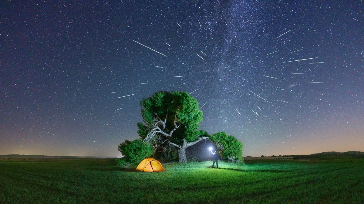 Solar eclipse and meteor streaks combining in dark night sky over landscape