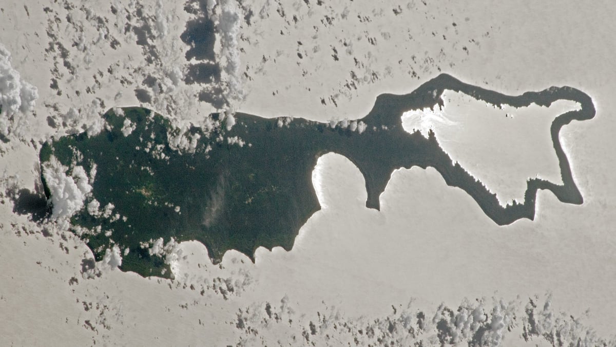 Aerial view of Rennell Island with silvery sunglint reflecting off ocean and lake waters